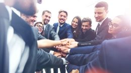Diverse group of business people piling their hands in the center of a circle