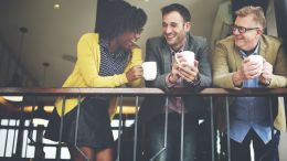 Diverse coworkers talk and network over coffee in their office
